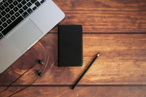 Acostado Portátil Lápiz Cuaderno Negro Sobre Fondo Madera Marrón Oscuro — Foto de Stock