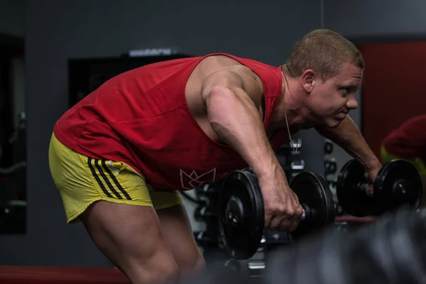Spor salonunda kaslı genç adam eğitimi. Dumbbell egzersiz. Spo