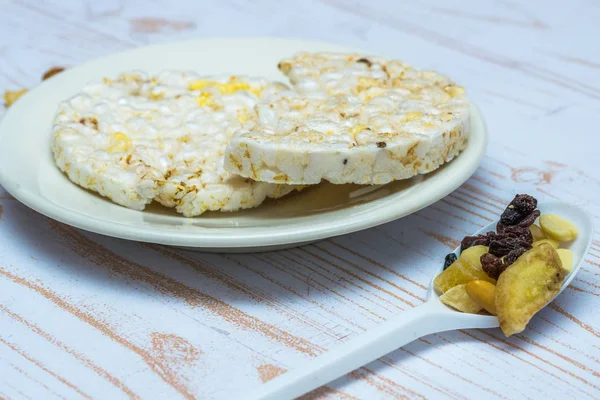 Close-up of rice waffles on plate and dried fruits on the spoon.