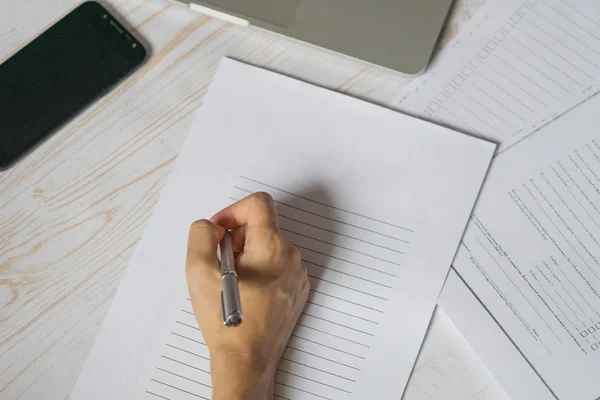 Mano de la joven sosteniendo la pluma encima de la lista en blanco de papel. Sc — Foto de Stock