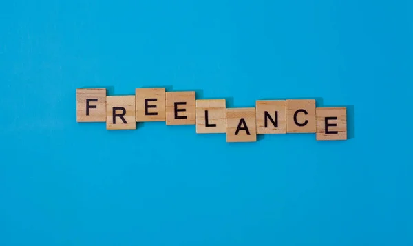 the word freelancer. Wooden letters on a blue background. Human resource management, recruitment and recruitment concept.