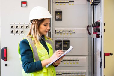 Kontrol odasındaki kontrol panelinin önünde duran genç iş kadını.