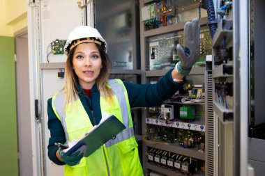 Kontrol odasındaki kontrol panelinin önünde duran genç iş kadını.