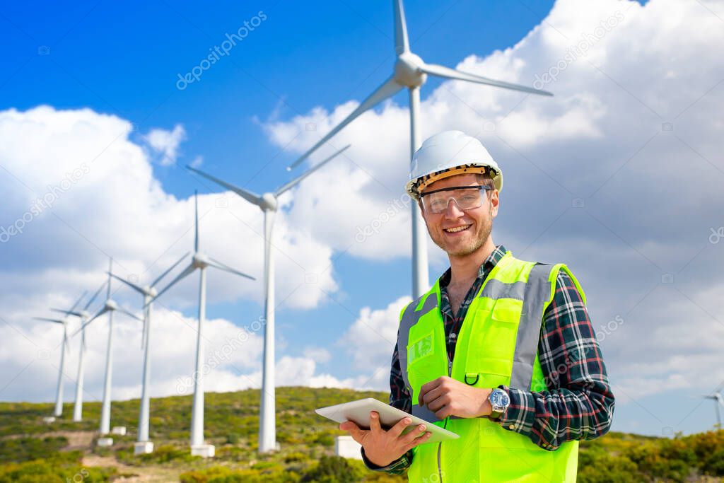 Young worker looking and checking wind turbines at field