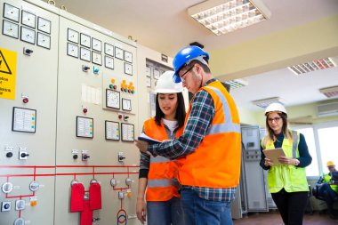 Enerji kontrol odasında çalışan genç bakım mühendisi ekibi.