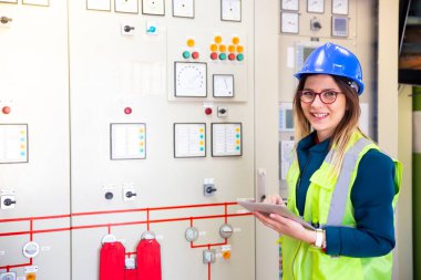 Kontrol odasındaki kontrol panelinin önünde duran genç iş kadını.