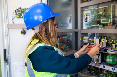 Genç bayan bakım mühendisi voltajı dijital çoklu metre ile test ediyor