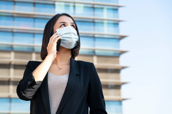 Woman with mask talks on the phone for business