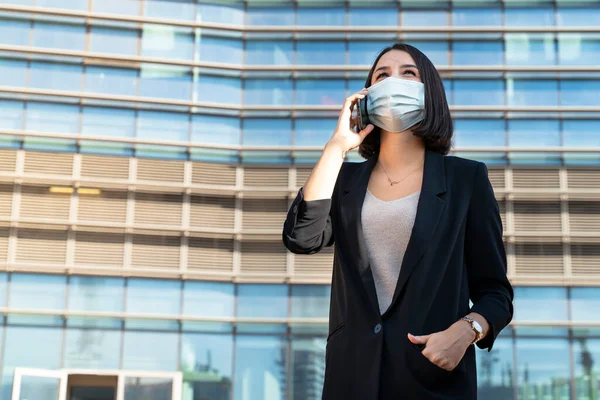 Woman with mask talks on the phone for business