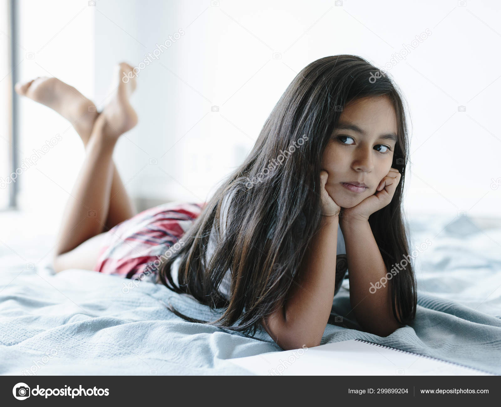 Young girl lying on bed looking to the left. Stock Photo by ...