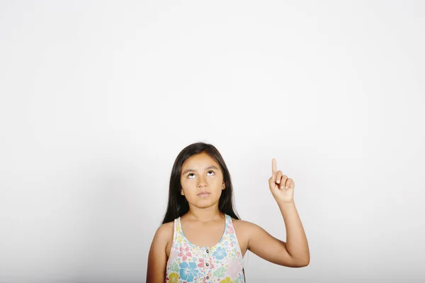 Jong meisje wijzend aan de rechterkant van het scherm op witte achtergrond. — Stockfoto