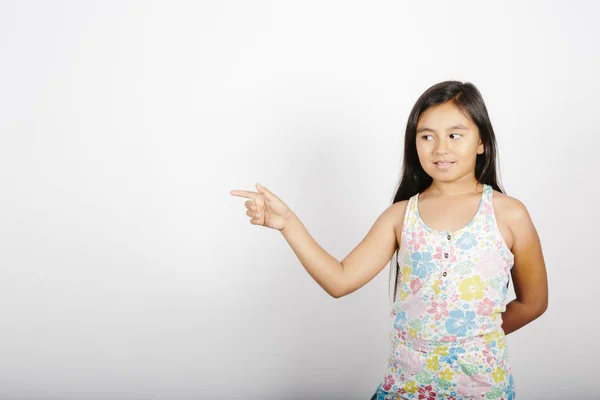 Niña apuntando a la izquierda de la pantalla sobre fondo blanco . — Foto de Stock