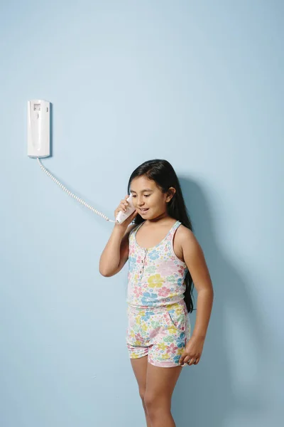 Young girl answers the intercom over blue background