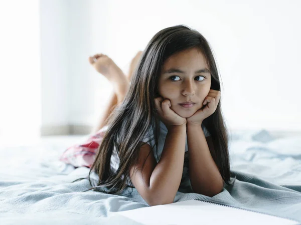 Young girl lying on bed looking to the left. — Stock Photo, Image