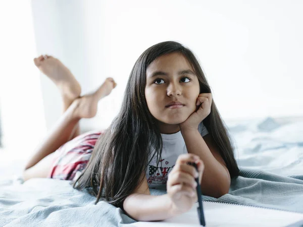 Young girl lying on bed looking up. — Stock Photo, Image