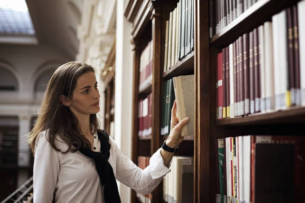 Student szuka książki w bibliotece. — Zdjęcie stockowe