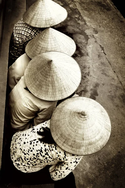 Vietnamese ladies sitting in a row showing their hats — Stock Photo, Image