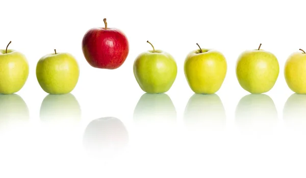 Manzana roja que sobresale de la fila de manzanas verdes . — Foto de Stock