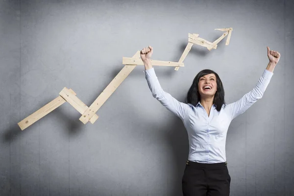 Mujer de negocios muy alegre delante del gráfico de negocios ascendente . — Foto de Stock