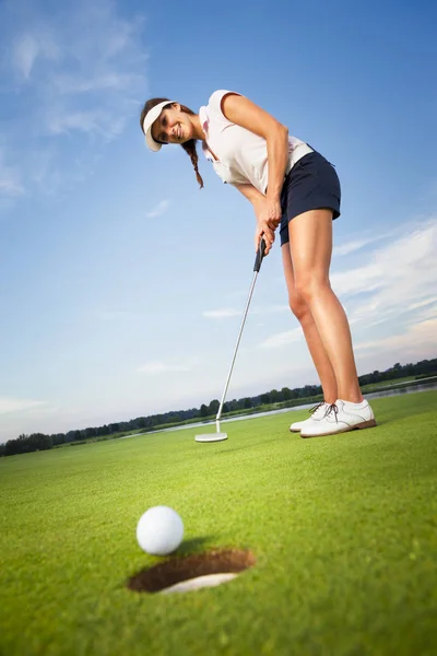 Happy girl golfer putting ball into hole. — Stock Photo, Image