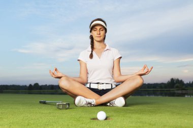 Kız golfçü golf sahasında yoga duruş oturan.