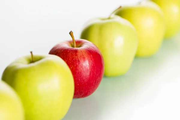 Roter Apfel ragt aus einer Reihe grüner Äpfel heraus. — Stockfoto