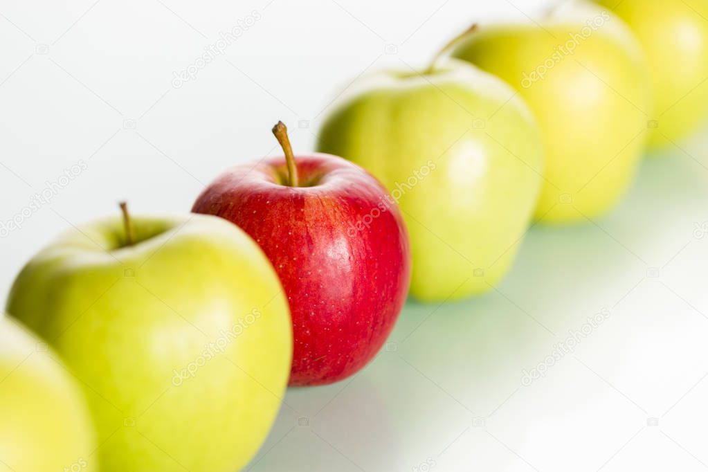 Red apple standing out from row of green apples.