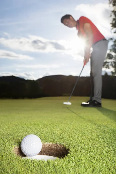Golfçü fincan içine topu koyarak.