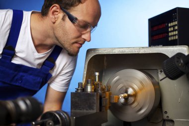 Close up of technician working on lathe machine. clipart