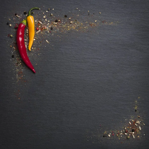 Chili peppers and spices on slate stone.