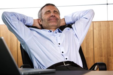 Ofis sandalyesinde rahatlatıcı Gülümseyen yönetici.