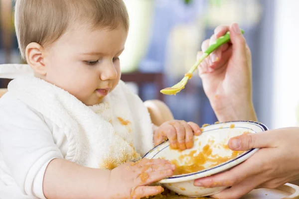 Zoete rommelig baby jongen spelen met eten tijdens het eten. — Stockfoto