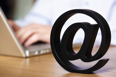 Ofis masasında oturan ve dizüstü bilgisayar da tek başına mektup sembolize internet kullanarak.