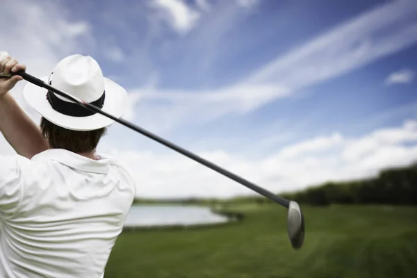 Close-up of male golf player with hat teeing-off at beautiful golf course.