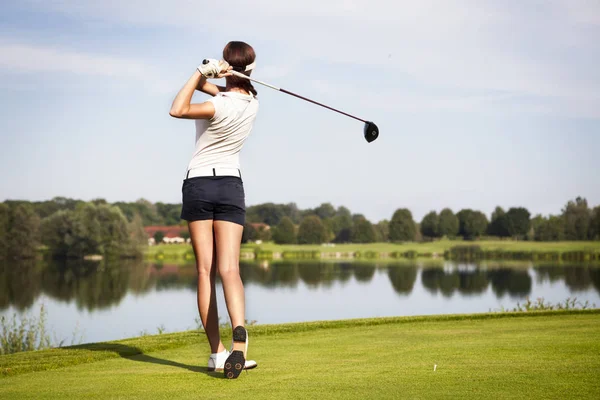 Sürücü teeing-off ile Kız golf oyuncusu tee-off göl üzerinde ateş etmek, arkadan görmek.