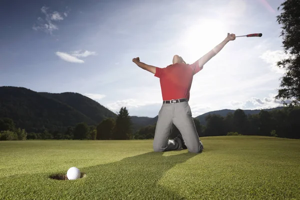 Erkek golf oyuncusu diz ve kollar elinde atıcı ile yükseltilmiş kazanan golf yeşil golf topu fincan içine düşer gibi overjoyed olmak poz.
