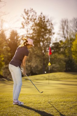 Bayrağa doğru fırlatan kadın golfçü.