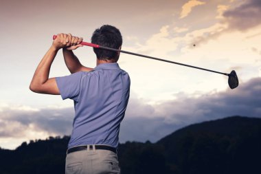 Golfçü gün batımında teeing.