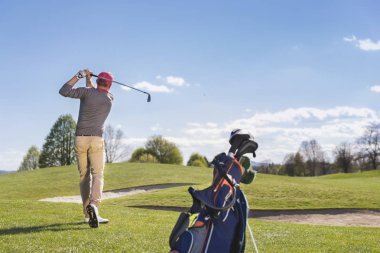 Genç adam golf sahasında oynuyor.