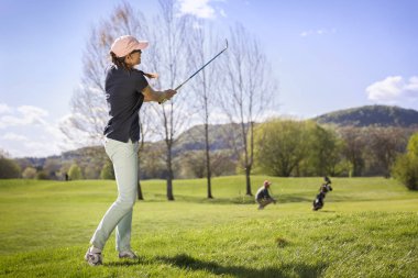 Kadın golfçü atış yapıyor.