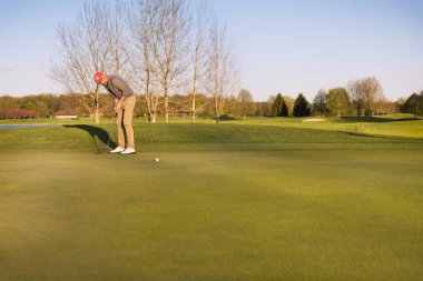 Golfçü yeşile vuruyor.