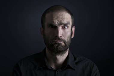 Siyah arka planda kafası karışmış bir adamın portresi.