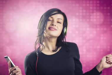 Smiling girl listening to music with earphones and dancing. clipart