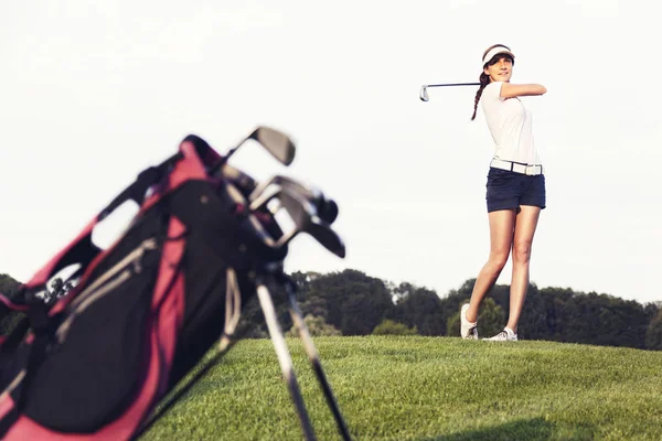 Kız golfçü golf sahasında topa vurma.