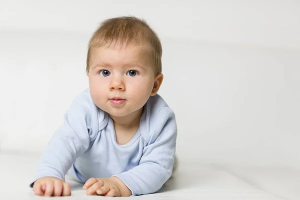 Portrait of adorable baby boy lying on white couch. — Stock Photo, Image