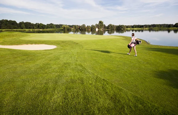 골프 백을 들고 골프 코스를 걷는 소녀 골퍼. — 스톡 사진