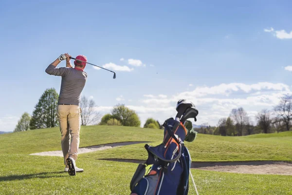 Genç adam golf sahasında oynuyor.