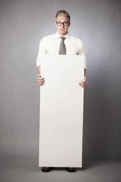 Empresario trastornado sosteniendo panel blanco vacío . — Foto de Stock