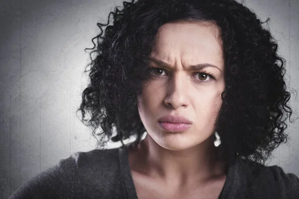 Closeup portrait of a frowning woman, being angry and mad, isolated on grey background.