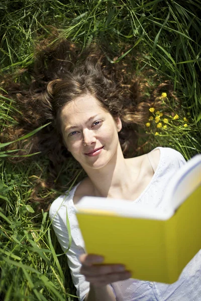 牧草地で読書している女 — ストック写真